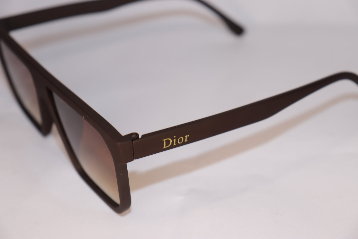 Brown sunglasses with 'Dior' logo on a white background