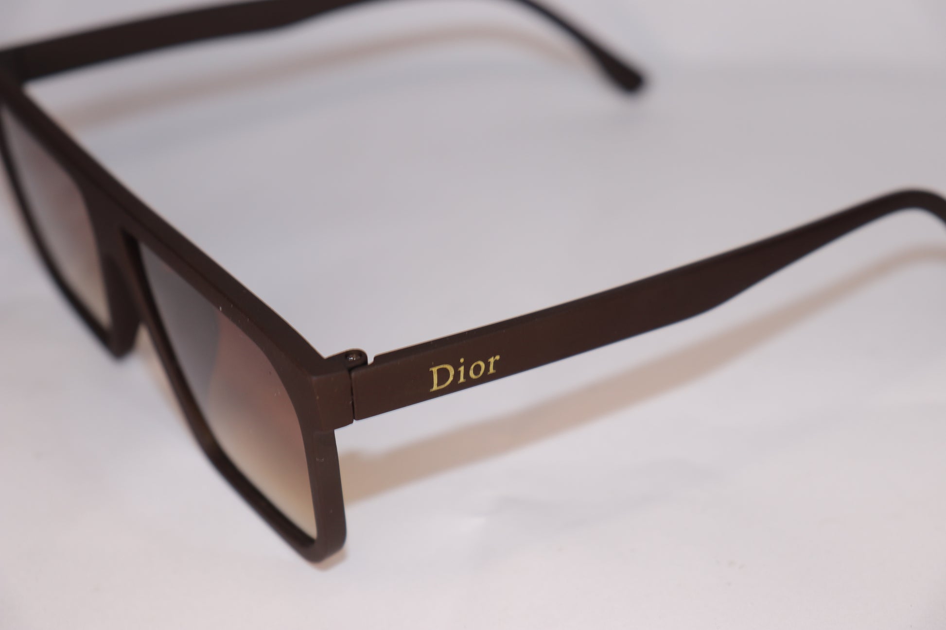 Brown sunglasses with 'Dior' logo on a white background